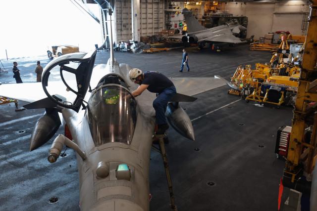 A French Navy officer works on a Marine Rafale fighter aircraft on the hangar deck of the Charles de Gaulle aircraft carrier as it returns from its 'Lafayette 26' mission near Bonifacio off the coast of the French island of Corsica, southern France on July 9, 2026. (Photo by Pascal POCHARD-CASABIANCA / AFP)