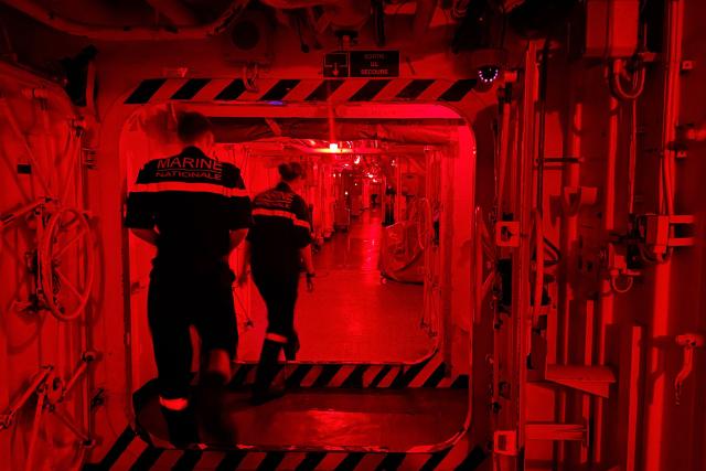 French Navy officers walk down at night in a corridor of the Charles de Gaulle aircraft carrier as it returns from its 'Lafayette 26' mission near Bonifacio off the coast of the French island of Corsica, southern France on July 9, 2026. (Photo by Pascal POCHARD-CASABIANCA / AFP)