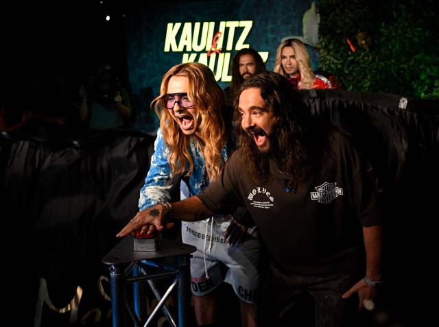 German musician Bill Kaulitz (L) and his twin brother Tom Kaulitz (R) from the German band "Tokio Hotel" press a button to officially launch the display of their wax likenesses during the unveiling of their figures at Madame Tussauds wax museum in Berlin on July 12, 2026. (Photo by Tobias SCHWARZ / AFP)