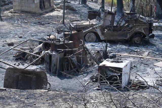 A burnt vehicle is seen amongst debris after a wildfire that killed at least 12 people, in Almocaizar, Almeria Province, on July 12, 2026. A wildfire that has killed at least 12 people in southern Spain was close to being brought under control Sunday, allowing hundreds of evacuated residents to return home as firefighters worked to fully stabilise the blaze, offficials said. Authorities have kept the death toll at 12 and cautioned that the number of missing people remains uncertain until autopsies and the identification of recovered bodies are completed. (Photo by JOSE JORDAN / AFP)