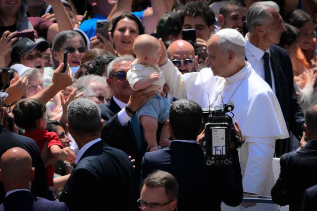 Pope Leo XIV blesses a baby as he greets the crowd after the Angelus prayer from the entrance of the Apostolic Palace in Piazza della Liberta (Liberty Square) at the summer papal residence in Castel Gandolfo on 12 July 2026. (Photo by Tiziana FABI / AFP)