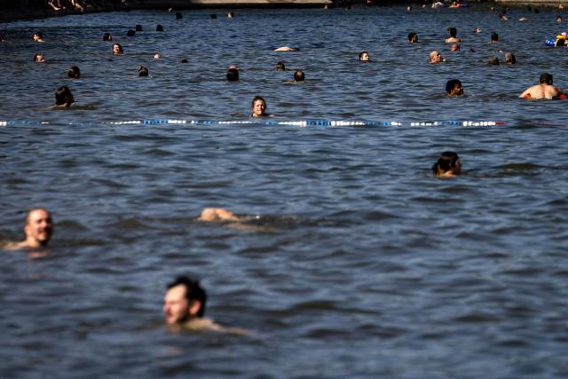 People swim in the Canal Saint-Martin as France experiences a heatwave, in Paris on July 12, 2026. (Photo by Behrouz MEHRI / AFP)