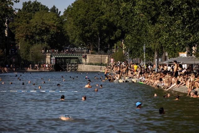 People swim in the Canal Saint-Martin as France experiences a heatwave, in Paris on July 12, 2026. (Photo by Behrouz MEHRI / AFP)