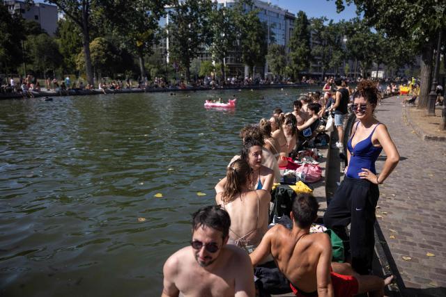 People sit by the Canal Saint-Martin as France experiences a heatwave, in Paris on July 12, 2026. (Photo by Behrouz MEHRI / AFP)