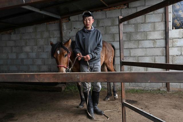 Fourteen-year-old jockey Zolboo Gantumur prepares to practise horse riding ahead of the Naadam festival on the outskirts of Ulaanbaatar on June 23, 2026. Six-year-old Hurts Gantumur raced across the Mongolian grasslands astride a galloping horse, training to become a child jockey in the country's biggest cultural festival. (Photo by Adek BERRY / AFP) / To go with 'Mongolia-Festival-Jockey' Visual story by Mungunsor Purevsuren