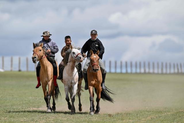 Child jockey six-years-old Hurts Gantumur (C) and boys from the neighbourhood practise horse riding ahead of the Naadam festival on the outskirts of Ulaanbaatar on June 23, 2026. Six-year-old Hurts Gantumur raced across the Mongolian grasslands astride a galloping horse, training to become a child jockey in the country's biggest cultural festival. (Photo by Adek BERRY / AFP) / To go with 'Mongolia-Festival-Jockey' Visual story by Mungunsor Purevsuren