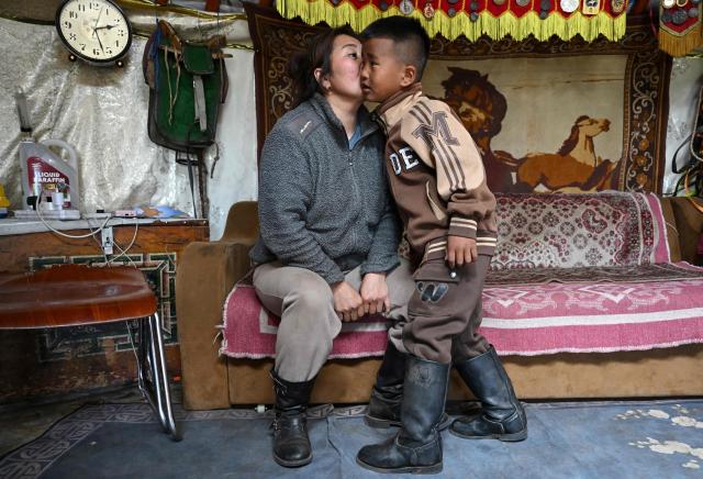Six-year-old jockey Hurts Gantumur gets a kiss from his mother prior to practising horse riding on the outskirts of Ulaanbaatar on June 23, 2026. Six-year-old Hurts Gantumur raced across the Mongolian grasslands astride a galloping horse, training to become a child jockey in the country's biggest cultural festival. (Photo by Adek BERRY / AFP) / To go with 'Mongolia-Festival-Jockey' Visual story by Mungunsor Purevsuren