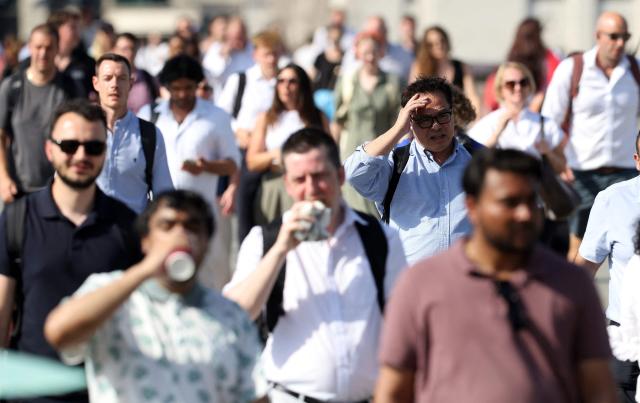(FILES) Commuters walk in the sun as they cross London Bridge during a heatwave in central London on June 24, 2026. At least 2,700 people could have died in England and Wales as a result of heatwaves that struck in May and June, according to a study released on July 13, 2026. (Photo by Toby Shepheard / AFP)