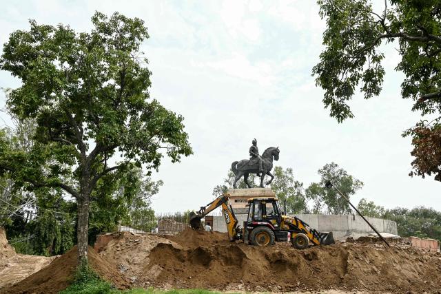 A worker operates a JCB machine during a beautification drive around the statue of Maharaja Ranjit Singh at a garden in Amritsar on July 13, 2026. (Photo by Narinder NANU / AFP)