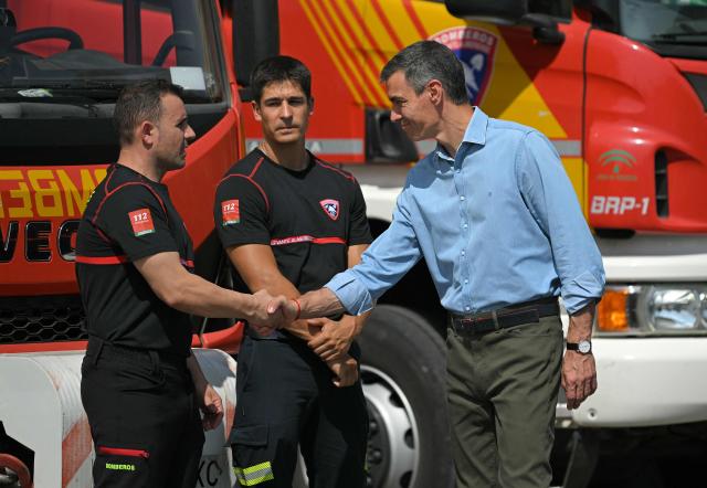 Spain's Prime Minister Pedro Sanchez (R) shakes hands with emergency services personnel as he arrives in the area of a wildfire that killed at least 13 people, at the command post set in Turre, Almeria Province, on July 13, 2026. The toll from the deadly wildfires in southern Spain rose to 13 on July 12, 2026 after a British woman died of her injuries in hospital, officials in Andalusia region announced. (Photo by JORGE GUERRERO / AFP)