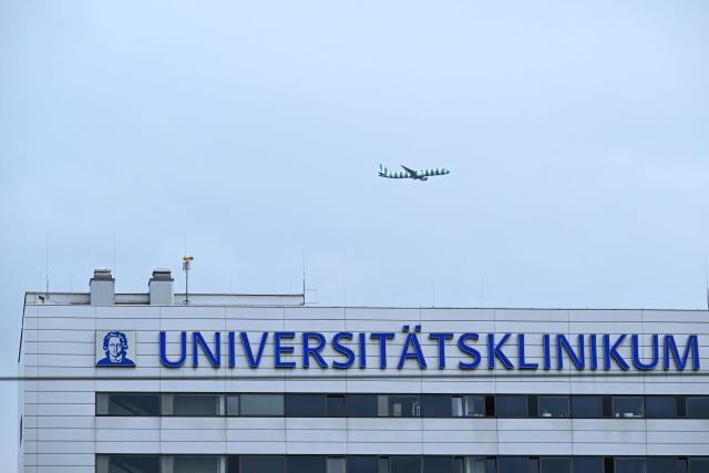 (FILES) An airplane flies over the university hospital (Universitätsklinikum Frankfurt) in Frankfurt am Main, western Germany, on May 11, 2026. Less than two months after the arrival of the first US Ebola patient from the Democratic Republic of the Congo, a second patient has been brought to Germany. According to the Federal Ministry of Health, the patient was admitted to the university hospital in Frankfurt am Main on July 13, 2026. He is being treated in "complete isolation" in the special isolation unit there. Consequently, there is "no risk whatsoever" to the general public or to other patients. (Photo by Kirill KUDRYAVTSEV / AFP)