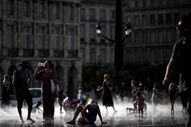 A pedestrian drinks water on the Miroir d'eau reflecting pool amid a heatwave, in Bordeaux, southwestern France on July 12, 2026. Twenty-six million French people remain under a red heatwave alert ahead of a let-up on Tuesday, though this will not mark the end of the third heatwave to hit France in less than two months. (Photo by Christophe ARCHAMBAULT / AFP)