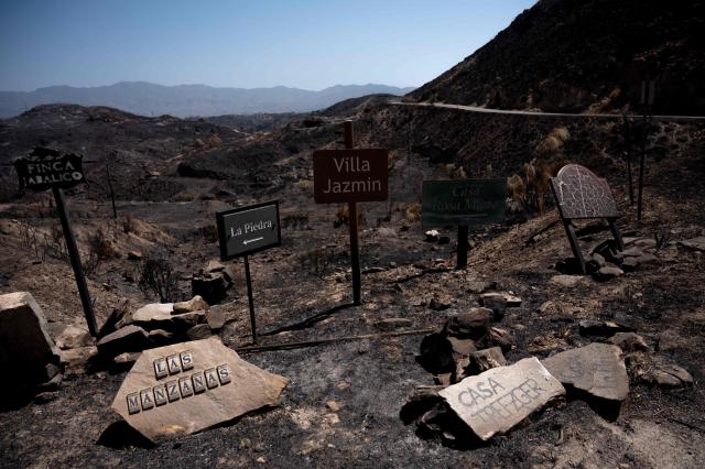 Placards with the names of villas are seen amongst the burnt landscape days after a wildfire that killed at least 13 people, in Bedar, near Almeria on July 13, 2026. Three Britons and one national each from France, Belgium and Spain are among the 13 victims of one of the deadliest Spanish wildfires in recent times, authorities said on July 13 2026. The blaze that broke out on July 9, 2026, has transformed picturesque rural settlements into ghost towns and left a trail of destruction in the southeastern province of Almeria, home to many foreign residents near the Mediterranean coast. The authorities have cautioned that the number of missing people remains uncertain until autopsies and the identification of bodies are completed.  (Photo by JORGE GUERRERO / AFP)