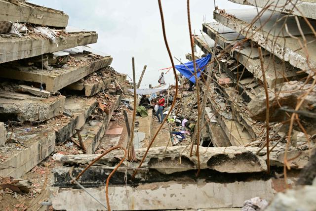 Residents remain between the slabs of a collapsed building in Caraballeda, La Guaira state, Venezuela, on July 13, 2026, following twin earthquakes that struck the region. The official death toll from Venezuela's devastating twin earthquakes rose to nearly 4,500 on July 12, 2026, as the government reported more than 19,500 people were now living in camps due to the destruction. (Photo by MARTIN BERNETTI / AFP)