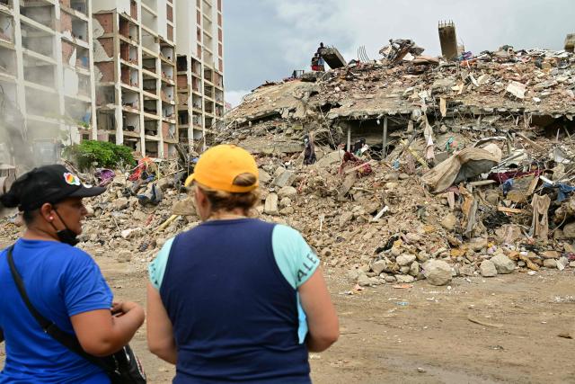 Residents watch rescue and recovery operations at the site of a collapsed building in Caraballeda, La Guaira state, Venezuela, on July 13, 2026, following twin earthquakes that struck the region. The official death toll from Venezuela's devastating twin earthquakes rose to nearly 4,500 on July 12, 2026, as the government reported more than 19,500 people were now living in camps due to the destruction. (Photo by MARTIN BERNETTI / AFP)