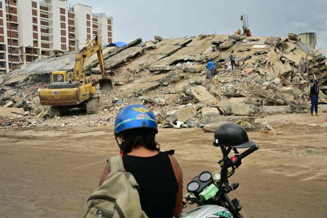 Relatives of missing people remain near a backhoe used at a collapsed building in Caraballeda, La Guaira State, Venezuela on July 13, 2026, following the June 24 twin earthquakes. The official death toll from Venezuela's devastating twin earthquakes rose to nearly 4,500 on July 12, 2026, as the government reported more than 19,500 people were now living in camps due to the destruction. (Photo by MARTIN BERNETTI / AFP)