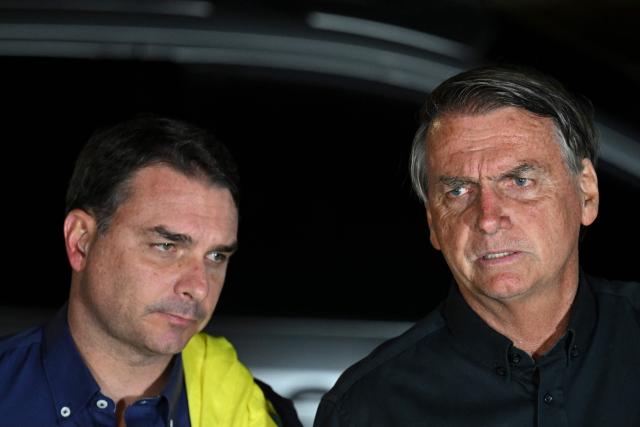 (FILES) Brazilian President and re-election candidate Jair Bolsonaro (R) speaks next to his son Flavio (L) after learning the results of the legislative and presidential election in Brasilia, on October 2, 2022. Brazil's top court barred on July 13, 2026 presidential hopeful Flavio Bolsonaro from visiting his father, the former president Jair Bolsonaro, who is under house arrest, until after the first round of October elections. (Photo by EVARISTO SA / AFP)