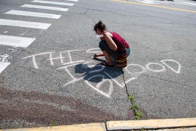 A person writes in chalk "this is blood" near the scene of a shooting where a federal officer shot and killed a person earlier in the day in Biddeford, Maine on July 13, 2026. A US immigration officer on Monday fatally shot a man identified by rights groups as a 26-year-old Colombian, an incident likely to fuel criticism of President Donald Trump's deportation drive. The shooting happened in Biddeford, a town of 22,000 people in the northern state of Maine, and comes a week after an Immigration and Customs Enforcement (ICE) agent shot dead a Mexican man in Texas. (Photo by Joseph Prezioso / AFP)