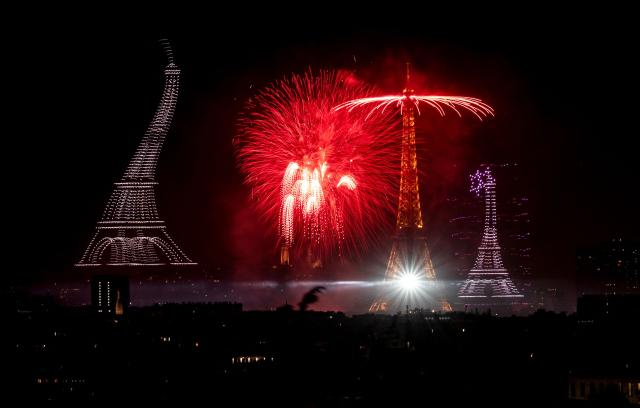 Fireworks and drones light up the sky around the Eiffel Tower during a choreographed show marking Bastille Day in Paris on July 13, 2026, on the eve of the annual Bastille Day parade in the French capital. (Photo by Martin BUREAU / AFP)