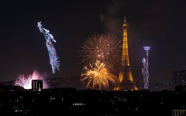 Fireworks and drones light up the sky around the Eiffel Tower during a choreographed show marking Bastille Day in Paris on July 13, 2026, on the eve of the annual Bastille Day parade in the French capital. (Photo by Martin BUREAU / AFP)