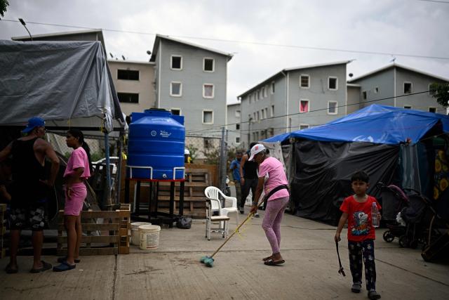 A woman sweeps the floor at a makeshift camp housing people displaced by the twin earthquakes in Maiquetia, La Guaira state, Venezuela, on July 13, 2026. The death toll from the twin earthquakes that struck Venezuela nearly three weeks ago has surpassed 4,500, while the number of injured remains at about 17,000, according to the latest government report released on July 13. (Photo by Federico PARRA / AFP)