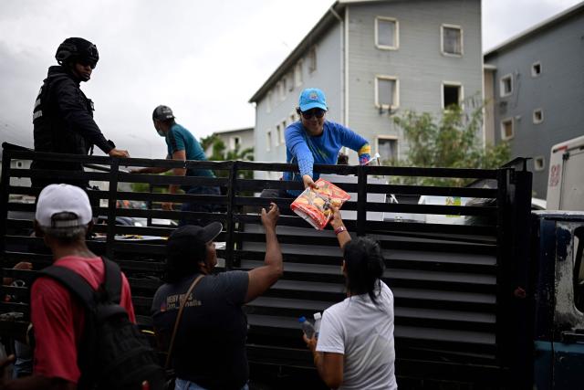 Volunteers distribute food to people displaced by the twin earthquakes at a makeshift camp in Maiquetia, La Guaira state, Venezuela, on July 13, 2026. The death toll from the twin earthquakes that struck Venezuela nearly three weeks ago has surpassed 4,500, while the number of injured remains at about 17,000, according to the latest government report released on July 13. (Photo by Federico PARRA / AFP)
