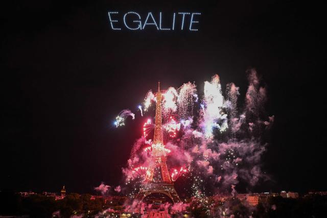 Fireworks explode as drones form the French word for "Equality", one of the three words of the French Republic motto: "Liberté, Égalité, Fraternité" around the Eiffel Tower during a choreographed show marking Bastille Day in Paris on July 13, 2026, on the eve of the annual Bastille Day parade in the French capital. (Photo by LOU BENOIST / AFP)