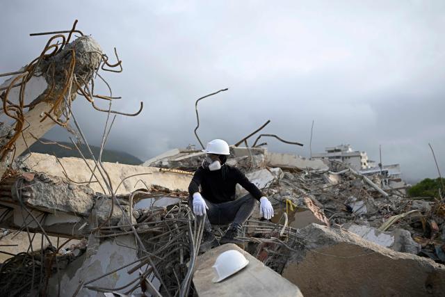 A rescue worker wearing protective gear pauses atop the rubble of a collapsed building in Los Corales, La Guaira state, Venezuela, on July 13, 2026, following twin earthquakes that struck the region. The death toll from the twin earthquakes that struck Venezuela nearly three weeks ago has surpassed 4,500, while the number of injured remains at about 17,000, according to the latest government report released on July 13. (Photo by Federico PARRA / AFP)