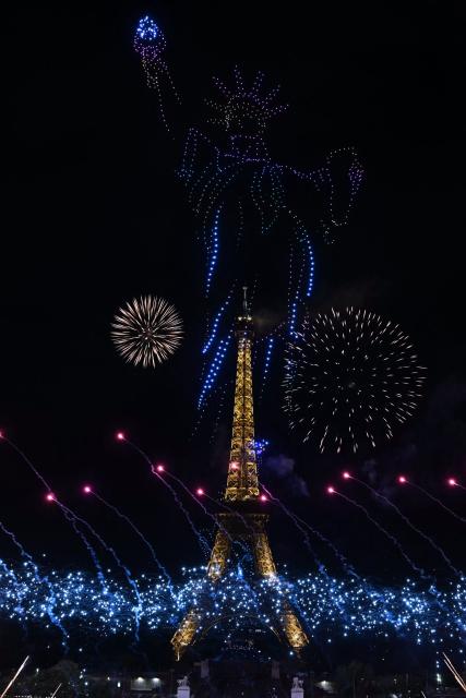 Fireworks explode as drones form a depiction of the Statue of Liberty around the Eiffel Tower during a choreographed show marking Bastille Day in Paris on July 13, 2026, on the eve of the annual Bastille Day parade in the French capital. (Photo by Lou BENOIST / AFP)