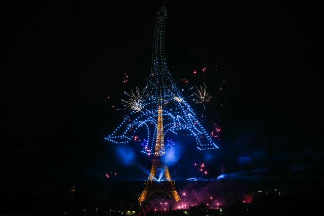 Fireworks and drones light up the sky around the Eiffel Tower during a choreographed show marking Bastille Day in Paris on July 13, 2026, on the eve of the annual Bastille Day parade in the French capital. (Photo by Lou BENOIST / AFP)