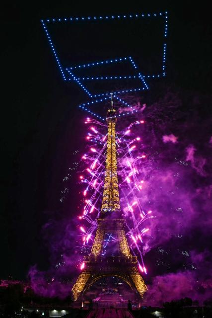 Fireworks and drones light up the sky around the Eiffel Tower during a choreographed show marking Bastille Day in Paris on July 13, 2026, on the eve of the annual Bastille Day parade in the French capital. (Photo by Lou BENOIST / AFP)