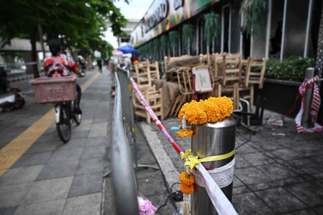 Flower garlands are left in front of the Rong Beer Na Lat Phrao bar in Bangkok on July 14, 2026. Investigators combed on July 13 through the wreckage of a huge fire at a Bangkok bar that killed at least 28 people, as relatives began the grim task of identifying the dead. (Photo by Lillian SUWANRUMPHA / AFP)