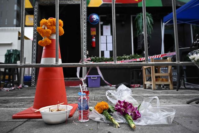 Offerings are left for victims in front of the Rong Beer Na Lat Phrao bar in Bangkok on July 14, 2026. Investigators combed on July 13 through the wreckage of a huge fire at a Bangkok bar that killed at least 28 people, as relatives began the grim task of identifying the dead. (Photo by Lillian SUWANRUMPHA / AFP)
