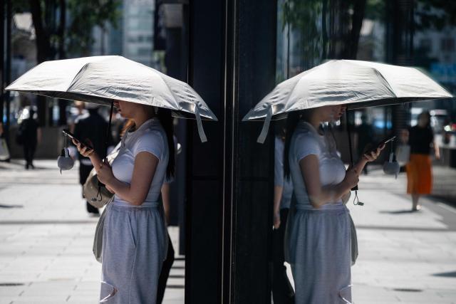 A woman uses an umbrella to take shelter from the sun on a hot morning in Tokyo on July 14, 2026. (Photo by Andrew CABALLERO-REYNOLDS / AFP)