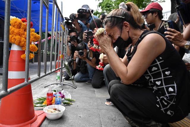 A woman, identified as Nid, prays for her deceased daughter Namtip Tubsook and her son-in-law Suwitcha Sirililung in front of the Rong Beer Na Lat Phrao bar in Bangkok on July 14, 2026. Investigators combed on July 13 through the wreckage of a huge fire at a Bangkok bar that killed at least 28 people, as relatives began the grim task of identifying the dead. (Photo by Lillian SUWANRUMPHA / AFP)