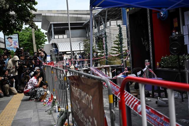 People pay their respects to victims of a fire in front of the Rong Beer Na Lat Phrao bar in Bangkok on July 14, 2026. Stricken relatives of the victims of a huge Bangkok bar fire claimed their bodies July 14 as the death toll rose to 30, even as others held out hope that their loved ones were still alive. (Photo by Lillian SUWANRUMPHA / AFP)
