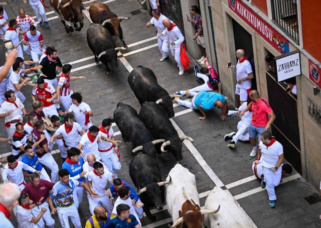 Participants run ahead of bulls from the Jandilla bull ranch during the eighth running of the bulls of the San Fermin festival in Pamplona, northern Spain, on July 14, 2026. Thousands of people every year attend the week-long festival and its famous 'encierros', or running of the bulls, in which six bulls are released at 8:00 a.m. evey day to run from their corral to the bullring through the narrow streets of the old town over an 850 meters (yards) course while runners ahead of them try to stay close to the bulls without falling over or being gored. (Photo by ANDER GILLENEA / AFP)