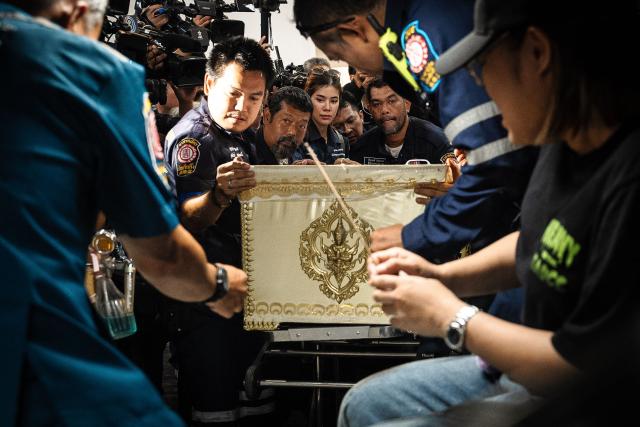 Responders transport a coffin bearing the remains of a victim killed in a bar fire, at the Police General Hospital in Bangkok on July 14, 2026. Grieving relatives of the victims of a huge Bangkok bar fire claimed their bodies on July 14 as the death toll rose to 30, even as others held out hope that missing loved ones were alive. (Photo by chanakarn LAOSARAKHAM / AFP)