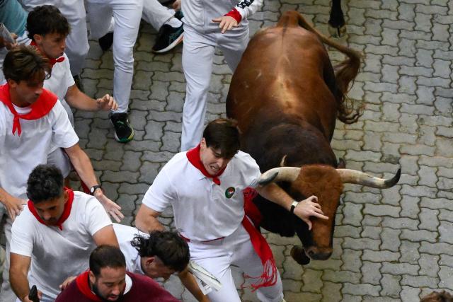 A runner barely evades a bull as participants run ahead of bulls from the Jandilla bull ranch during the eighth running of the bulls of the San Fermin festival in Pamplona, northern Spain, on July 14, 2026. Thousands of people every year attend the week-long festival and its famous 'encierros', or running of the bulls, in which six bulls are released at 8:00 a.m. evey day to run from their corral to the bullring through the narrow streets of the old town over an 850 meters (yards) course while runners ahead of them try to stay close to the bulls without falling over or being gored. (Photo by Miguel RIOPA / AFP)