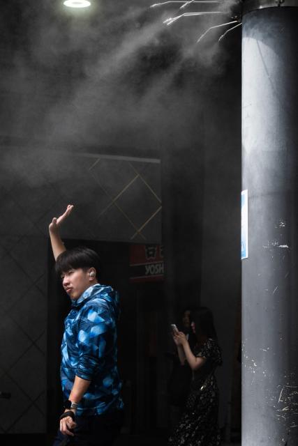 People walk under cooling mist sprayers on a hot day in Tokyo on July 14, 2026. (Photo by Andrew CABALLERO-REYNOLDS / AFP)
