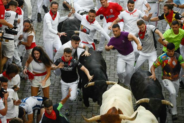Participants run ahead of bulls from the Jandilla bull ranch during the eighth running of the bulls of the San Fermin festival in Pamplona, northern Spain, on July 14, 2026. Thousands of people every year attend the week-long festival and its famous 'encierros', or running of the bulls, in which six bulls are released at 8:00 a.m. evey day to run from their corral to the bullring through the narrow streets of the old town over an 850 meters (yards) course while runners ahead of them try to stay close to the bulls without falling over or being gored. (Photo by Miguel RIOPA / AFP)
