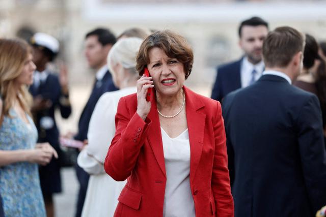 France's Agriculture Minister Annie Genevard speaks on the phone as she arrives to attend the annual Bastille Day military parade on the Champs-Elysees Avenue in Paris on July 14, 2026. (Photo by Benoit Tessier / POOL / AFP)