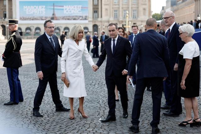 France's Prime Minister Sebastien Lecornu (C-R) speaks with French President's wife Brigitte Macron (C-L) upon arrival for the annual Bastille Day military parade on the Place de la Concorde in Paris on July 14, 2026. (Photo by Benoit Tessier / POOL / AFP)