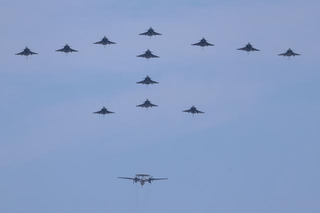 French Air and Space Army aircrafts, Rafale M fighter jets and a French Naval Aviation Grumman E-2C Hawkeye, perform a fly-over during the annual Bastille Day military air show over the Champs-Elysees Avenue in Paris on July 14, 2026. (Photo by Ludovic MARIN / AFP)