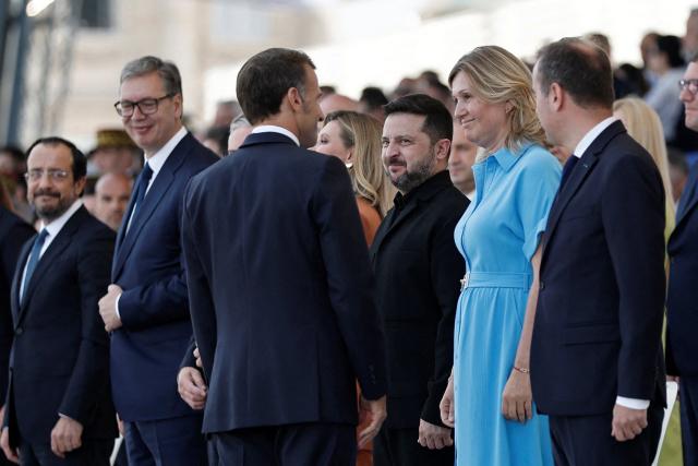 France's President Emmanuel Macron (C-L) greets Ukraine's President Volodymyr Zelensky (C-R) and President of the French National Assembly Yael Braun-Pivet (2R) on the Place de la Concorde during the annual Bastille Day military parade in Paris on July 14, 2026. (Photo by Benoit Tessier / POOL / AFP)