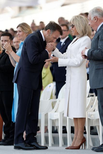 France's President Emmanuel Macron (C-L) kisses the hand of his wife Brigitte Macron on the Place de la Concorde during the annual Bastille Day military parade in Paris on July 14, 2026. (Photo by Benoit Tessier / POOL / AFP)