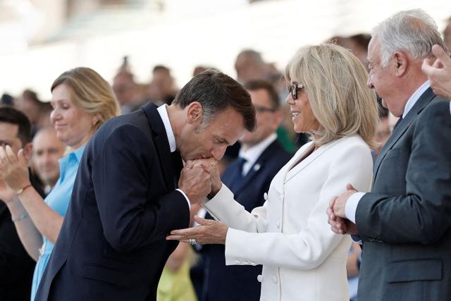 France's President Emmanuel Macron (C-L) kisses the hand of his wife Brigitte Macron on the Place de la Concorde during the annual Bastille Day military parade in Paris on July 14, 2026. (Photo by Benoit Tessier / POOL / AFP)