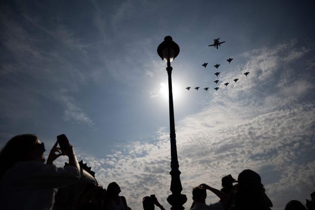 Spectators look at military aircrafts as they perform a flyover during the annual Bastille Day military parade in Paris on July 14, 2026. (Photo by Martin BUREAU / AFP)
