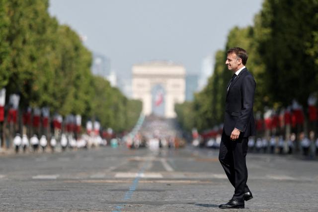 France's President Emmanuel Macron reviews troops on the Place de la Concorde with the Arc de Triomphe in the background during the annual Bastille Day military parade in Paris on July 14, 2026. (Photo by Benoit Tessier / POOL / AFP)
