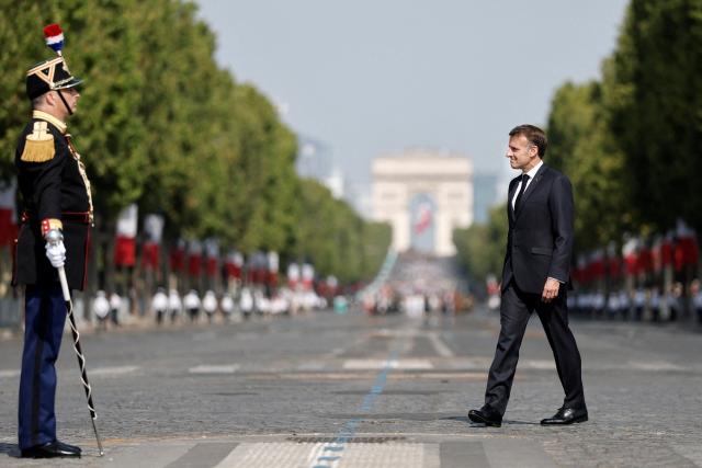 France's President Emmanuel Macron reviews troops on the Place de la Concorde with the Arc de Triomphe in the background during the annual Bastille Day military parade in Paris on July 14, 2026. (Photo by Benoit Tessier / POOL / AFP)